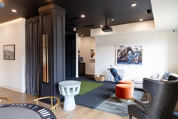 A living room with a grey sofa, a white chair and a red candle on a table at The Crest at South Point Apartments, Davenport 